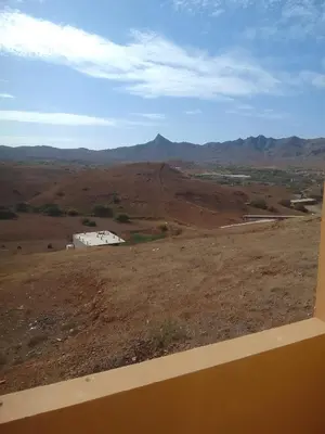 a view of a field with a barn and mountains at Ma maison de cha de marhina in Mindelo