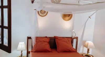a bedroom with a bed with red pillows and two lamps at Casa Cesaria Guest House in Sal Rei