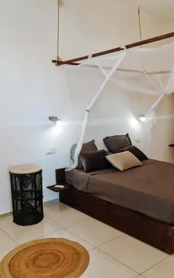 a bedroom with a large bed with a table and a rug at Casa Cesaria Guest House in Sal Rei