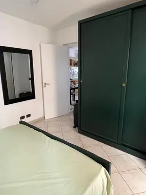a bedroom with a green door and a room with a table at Rosa dei venti 3 in Santa Maria