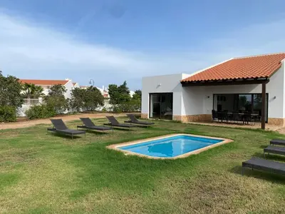 a backyard with a pool and chairs and a house at Casa de Cabo Verde in Santa Maria