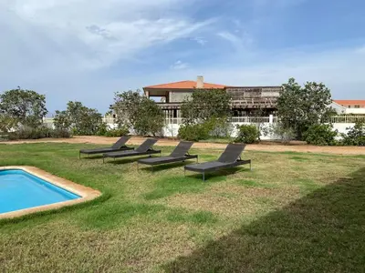 a group of lounge chairs sitting in the grass by a pool at Casa de Cabo Verde in Santa Maria