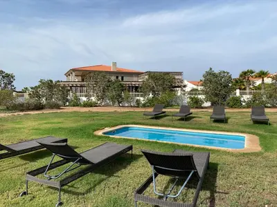 a group of chairs sitting around a swimming pool at Casa de Cabo Verde in Santa Maria