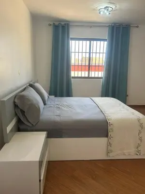 a bedroom with a bed with blue curtains and a window at Morabeza Lodge in Mindelo
