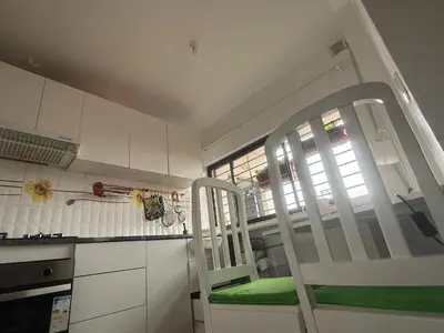 a kitchen with white cabinets and a chair and a window at Single & double Room for women only & Breakfast in Praia