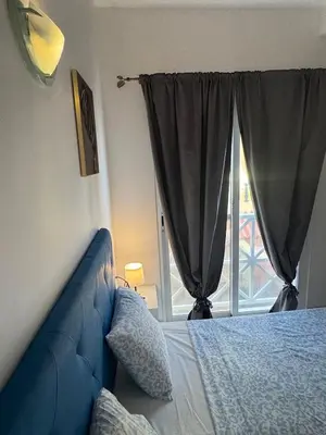 a bedroom with a blue couch and a window at Holiday Properties Ocean Breeze in Santa Maria