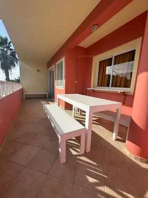 a room with a table and benches on a balcony at Holiday Properties Ocean Breeze in Santa Maria