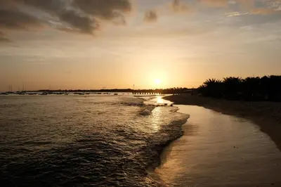 a sunset on a beach with the sun setting at Orange by No Stress ACWifi in Santa Maria