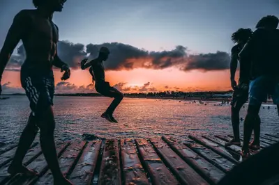 a group of people jumping into the water at the beach at Orange by No Stress ACWifi in Santa Maria