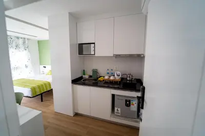 a kitchen with white cabinets and a bed in a room at GREEN STUDIO TARRAFAL - Ap 03 in Tarrafal