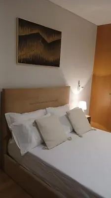 a bed with white pillows and a painting on the wall at Clara's Place - Faia Suite in Praia