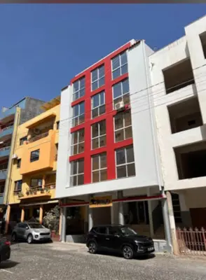 a red building with two cars parked in front of it at SweetLar in Praia