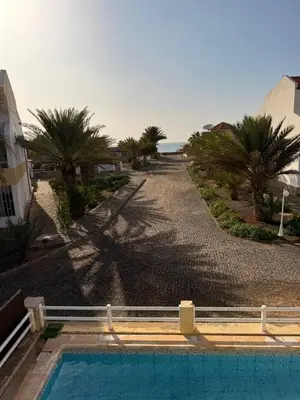 a swimming pool next to a road with palm trees at Murdeira Villa with Private Pool V164 by RPG Group in Beirona