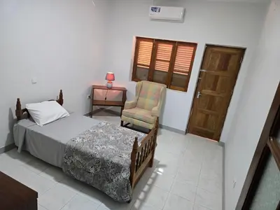 a bedroom with a bed and a chair and a door at Cozy 3 Bdr at Praia Da Laginha in Mindelo