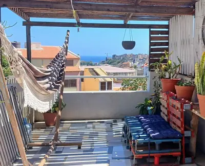 a hammock on a balcony with a view of the ocean at Cozy Apartment in Praia