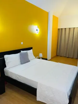 a bedroom with a large white bed with a yellow wall at Residencial Sol Point Art in Ponta do Sol