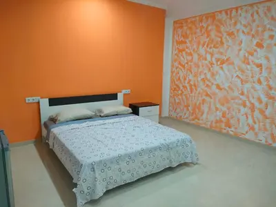 a bedroom with a bed with an orange wall at Residencial oliveira in Porto Novo