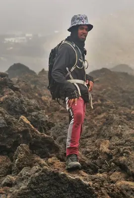 a man with a backpack standing on some rocks at Funco Du Santos in Portela