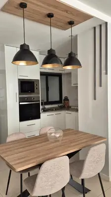 a kitchen with a wooden table with chairs and lights at kriola Breeze in Praia