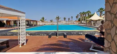 a person sitting in a chair next to a swimming pool at Apartamento em Condominio Privado in Beirona