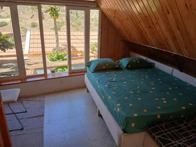 a bedroom with a bed with a green comforter and windows at Paraiso das ilhas in Ribeirão Chiqueiro