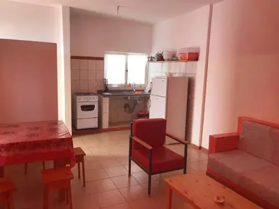 a kitchen with a refrigerator and a table and a couch at Maio Relax in Vila do Maio