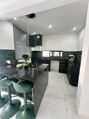 a kitchen with a black counter and green stools at Belle maison Cosy et Moderne in Praia
