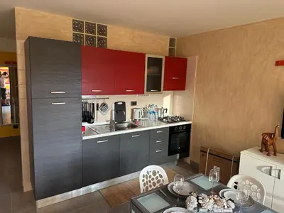 a kitchen with red cabinets and a table in it at Brisa Meridiana in Santa Maria
