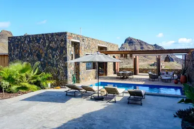 a patio with chairs and an umbrella next to a pool at Casa Vinti9 in Mindelo