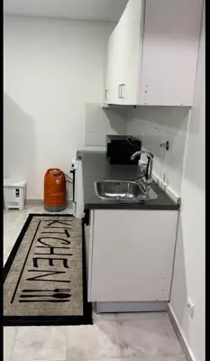 a kitchen with white cabinets and a sink and a rug at Micaya in Praia
