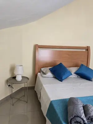 a bedroom with a bed with blue pillows and a table at Diva Apartamento in Praia