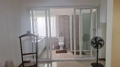 a bathroom with a shower and a toilet and a fan at Diva Apartamento in Praia