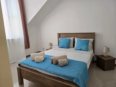 a bedroom with a large bed with blue pillows at Diva Apartamento in Praia