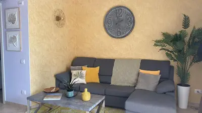 a living room with a couch and a clock on the wall at Tropical Palma in Santa Maria