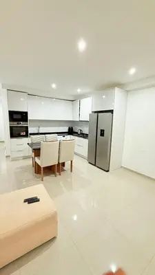 a white kitchen with a table and a refrigerator at Morabeza Home in Praia