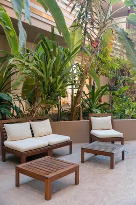 two chairs and a couch in a building with plants at Las Rochas Mindelo Aparthotel in Mindelo
