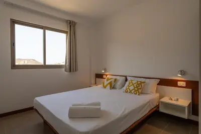 a bedroom with a large white bed with a window at Las Rochas Mindelo Aparthotel in Mindelo