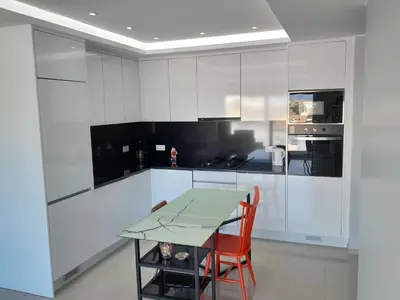 a kitchen with white cabinets and a table with a red chair at VISTA INVEST Apartamentos in Mindelo