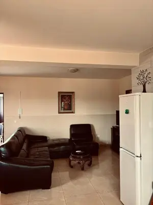 a living room with a black leather couch and a white refrigerator at Ferreira e Brito apartamentos in Espargos