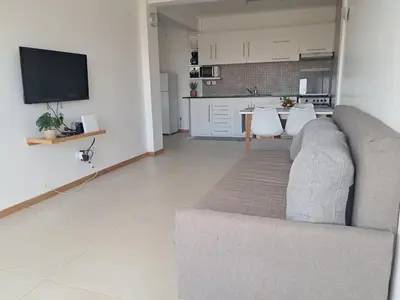 a living room with a gray couch and a kitchen at O Meu Aconchego em Montsú in Prainha