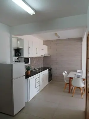 a kitchen with white cabinets and a table and chairs at O Meu Aconchego em Montsú in Prainha