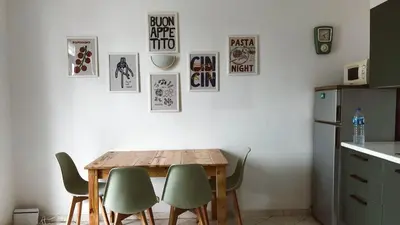 a dining room table with green chairs and posters on the wall at Verdes Anos - local accommodation in Santa Maria in Santa Maria