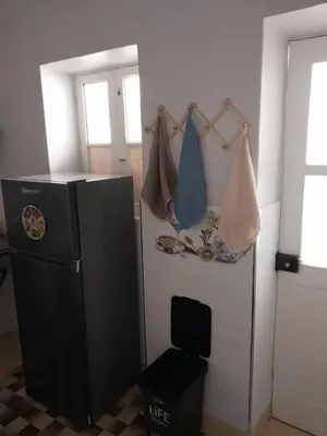 a kitchen with a refrigerator in a room with a window at Sol, Terra e Mar- No coração do Plateau in Praia