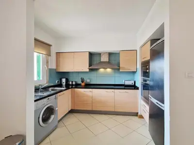 a kitchen with wooden cabinets and a washer at 1 bedroom apartment in Vila Verde Resort in Santa Maria