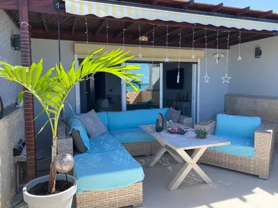 a patio with a blue couch and a table at Penthouse Lieblingsplatz - Favorite place frontline in Sal Rei