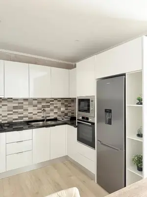 a kitchen with white cabinets and a stainless steel refrigerator at Spacious apartment in Praia Great for families in Montagarro