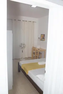 a bedroom with a bed and a table with a fan at Morabeza T2 City Center in Mindelo