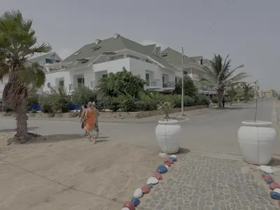 a woman walking down a street in front of some houses at Leme Bedje - Martine in Santa Maria