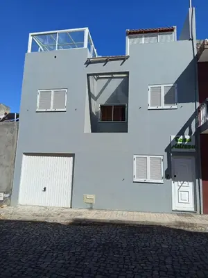 a white building with windows and doors on a street at Casa Melissa in Ponta do Sol