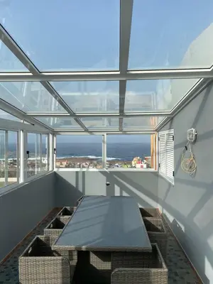 a dining room with a table and chairs and windows at Casa Melissa in Ponta do Sol